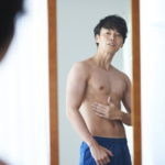 鏡で体をチェックする男性