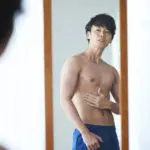 鏡で体をチェックする男性