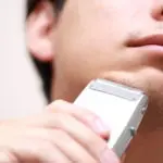 電気シェーバーを使う男性