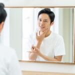 鏡で顔を見る男性