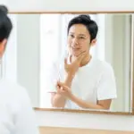 鏡で顔を見る男性