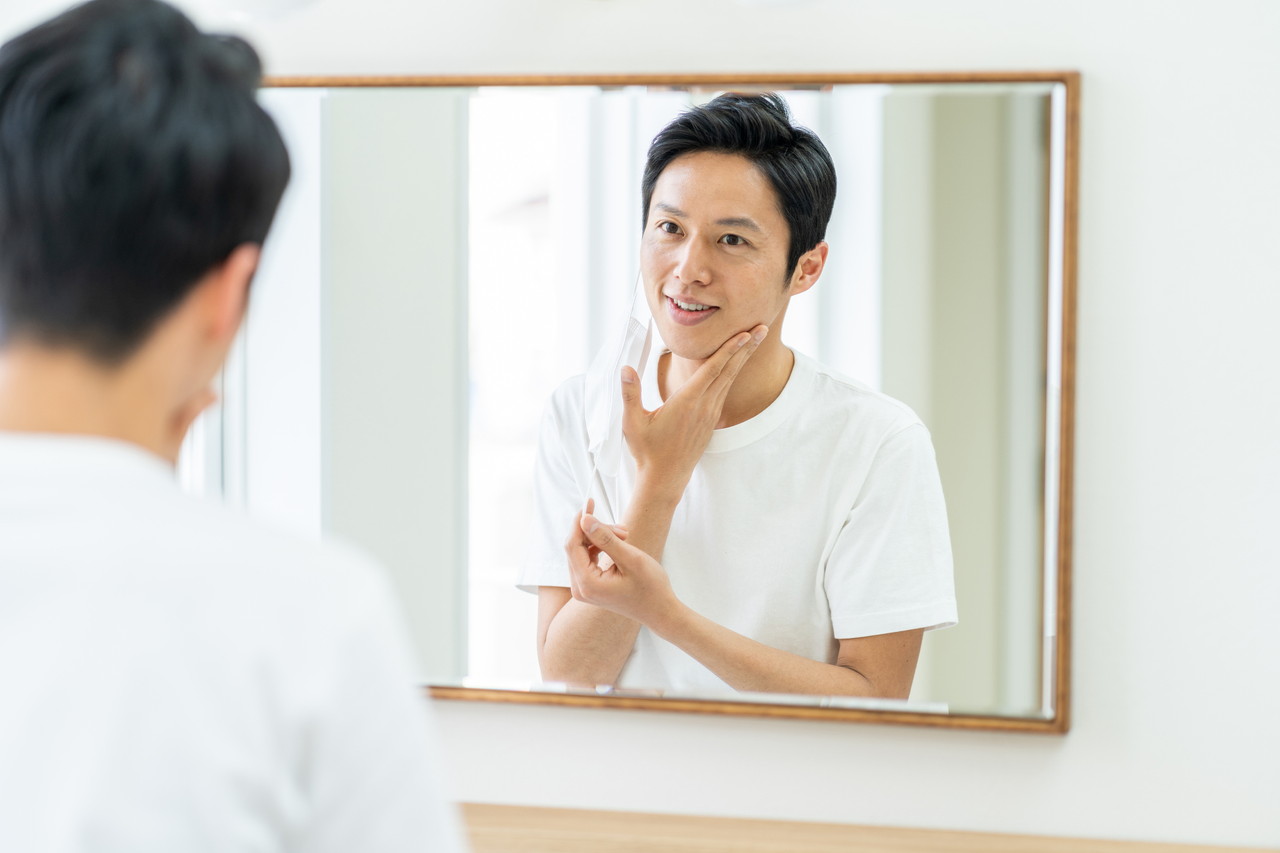 鏡で顔を見る男性